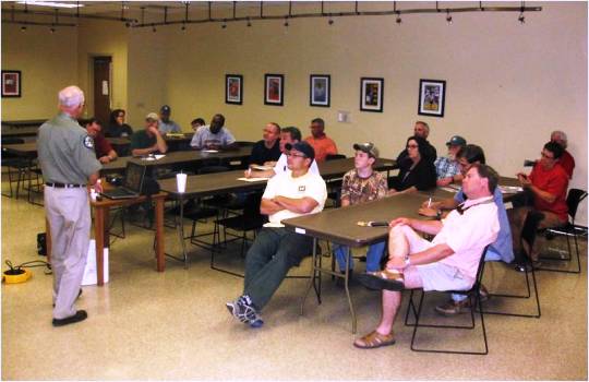 Group of people listen to a speaker at a pond assistance workshop