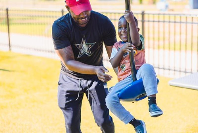 Father and son playing at a park swing